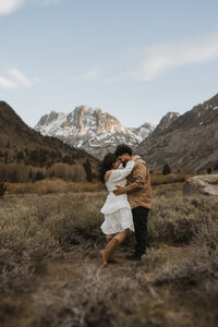 Couple holding eachother in front of a mountain