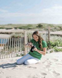 photographer with camera sitting in sand