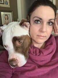 Testimonial photo of a woman taking a selfie with her deaf white and brown pitbull for Dogology University