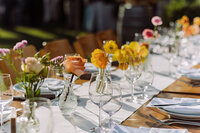 Bud vases for event tablescape featuring orange and yellow flowers