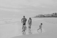 black and white photo of a family playing on the beach