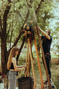 Wedding florist installing custom flowers on a wooden arch in Bend, Oregon