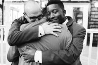 Three men in suits hugging