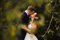 bride and groom share a kiss on their calgary wedding day in beautiful forrest