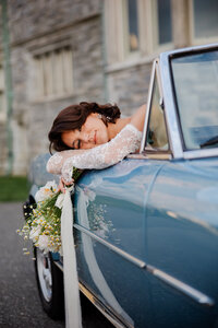 Photograph of Bride with bouquet  in antique car on wedding day.