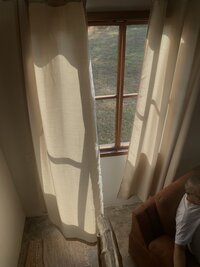 Linen curtains flowing against open window with morning light