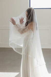 a wedding dress holding her veil at her wedding venue