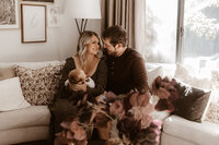 Mom and Dad smiling at each other while holding newborn baby and smiling in their living room