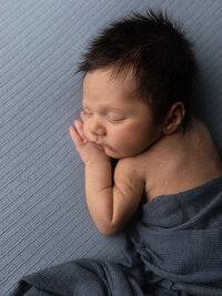 newborn baby boy wrapped in blue for photoshoot