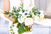 close up of bride holding a white flower wedding bouquet with green  leaves