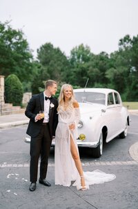 bride and groom standing in front of white old car