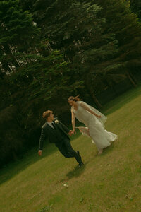 A newlywed couple looks at eachother with big smiles as they celebrate their marriage in front of a rustic cabin