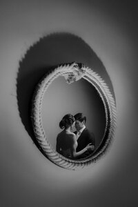 black and white creative portrait of newlywed couple reflected in a round mirror