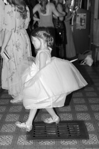 A little girl steps forward at a wedding, B&W