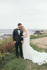 Bride in her dress and groom in tux in front of water