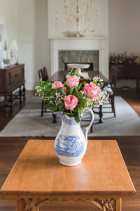 Pink roses in antique blue and white glass pitcher set on a table