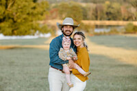 family portrait of young family holding one year old daughter in front of El Cerrito Lodge wedding and elopement venue in East Texas
