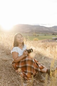 Meghan poses while holding a camera