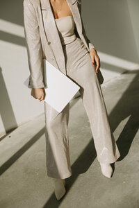 stylish woman fashion champagne suit holding laptop