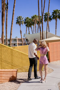 A vibrant and playful couple shares a lighthearted moment in the colorful setting of Palm Springs. With warm golden light, mid-century architecture, and a fun retro aesthetic, this fine art image captures the joy of love and connection in a sun-drenched paradise.