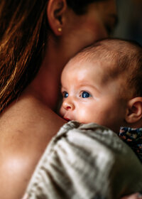 Two little girls lay on a blanket on their stomachs looking at each other and giggling in this family fall photography session/