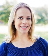 blonde haired woman smiling and wearing a blue shirt