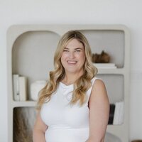 Brogan seated on a stool in a neutral room wearing business attire