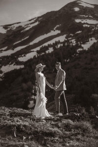 bride and groom holding hands on a mountain