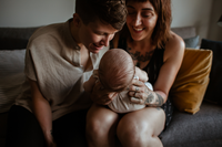 a queer couple holding their new baby
