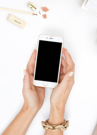 A woman's hands holding an iphone on a white table