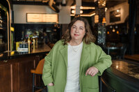 Woman in Kelowna cafe wearing colourful dress posing for brand photos.