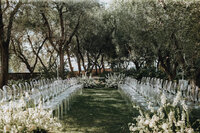 Elegant outdoor wedding ceremony with transparent chairs arranged toward a floral altar, ideal for a luxury destination wedding amid lush Italian greenery.
