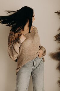 Portrait of a woman with dark hair and tattoos in a casual sweater and jeans in Mullingar, Ireland