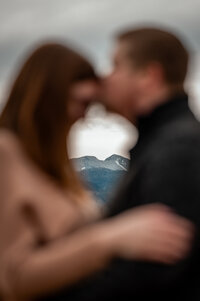 couple kissing with the mountains in the background 