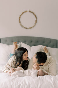 Mom and dad on laying on their stomachs on their bed with newborn baby laying infront of them.