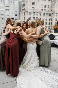 A group of girls getting together hugging the bride 