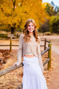 senior high school leaning on fence at Crescent Moon Ranch with fall leaves Sedona Julia Romano Photography