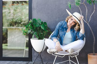 April wearing a sun hat, smiling and sitting with her head playfully tilted.