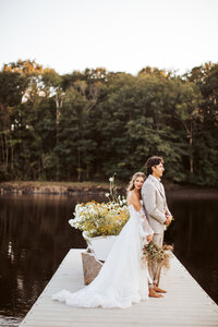 Bride and groom standing together on a flower-decorated dock overlooking the water during their Maine elopement.