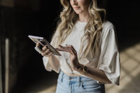 Branding photograph of a woman holding her phone and working.