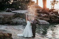 Bride and groom sharing a kiss on a wooden deck with breathtaking mountain views in the background during their outdoor elopement.