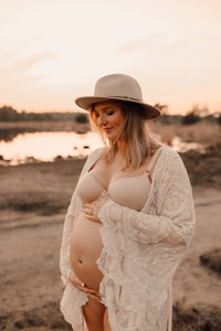 Zwangere vrouw in kimono poseert voor zwangerschapsshoot tijdens zonsondergang op de Kalmthoutse Heide