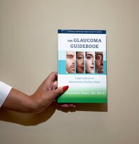 A person holding The Glaucoma Guidebook by Dr. Okeke, showcasing the book’s physical design and reinforcing its role as a practical tool for glaucoma patients seeking easy-to-understand information and guidance.