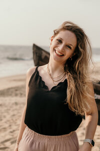 Ein Portrait von Karin lachend an einem Strand in einer lockeren Pose.