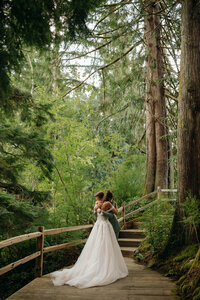 Bride and groom embracing during a first look on a forest boardwalk, surrounded by trees, captured by a Washington state wedding photographer.