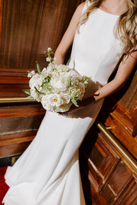 Bride standing in an elevator while holding her bridal bouquet