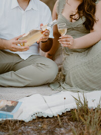 South Florida lifestyle photographer captures couple enjoying picnic and pouring drinks during cozy engagement session