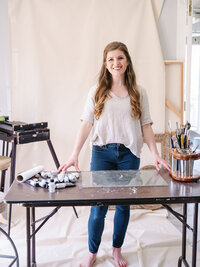 Stephanie Torregrossa Gaffney standing at table with paint & brushes to teach the Wedding Painter's Blueprint