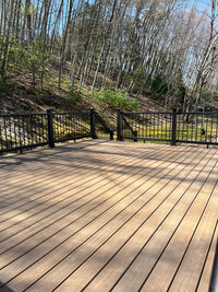 A dark natural wood looking composite deck with black railings built by a