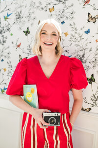 Headshot of Dr. Brooks, orthodontist in Nashville, TN, in a red outfit holding a vintage camera